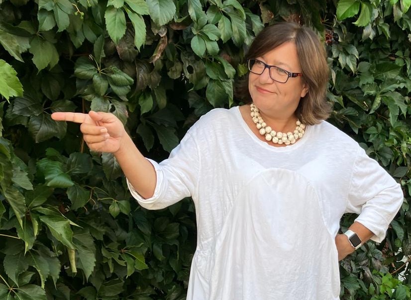 Karin Cvrtila von TILA Digital zeigt nach links auf die kostenlose Checkliste für dein Business in Zeiten von KI